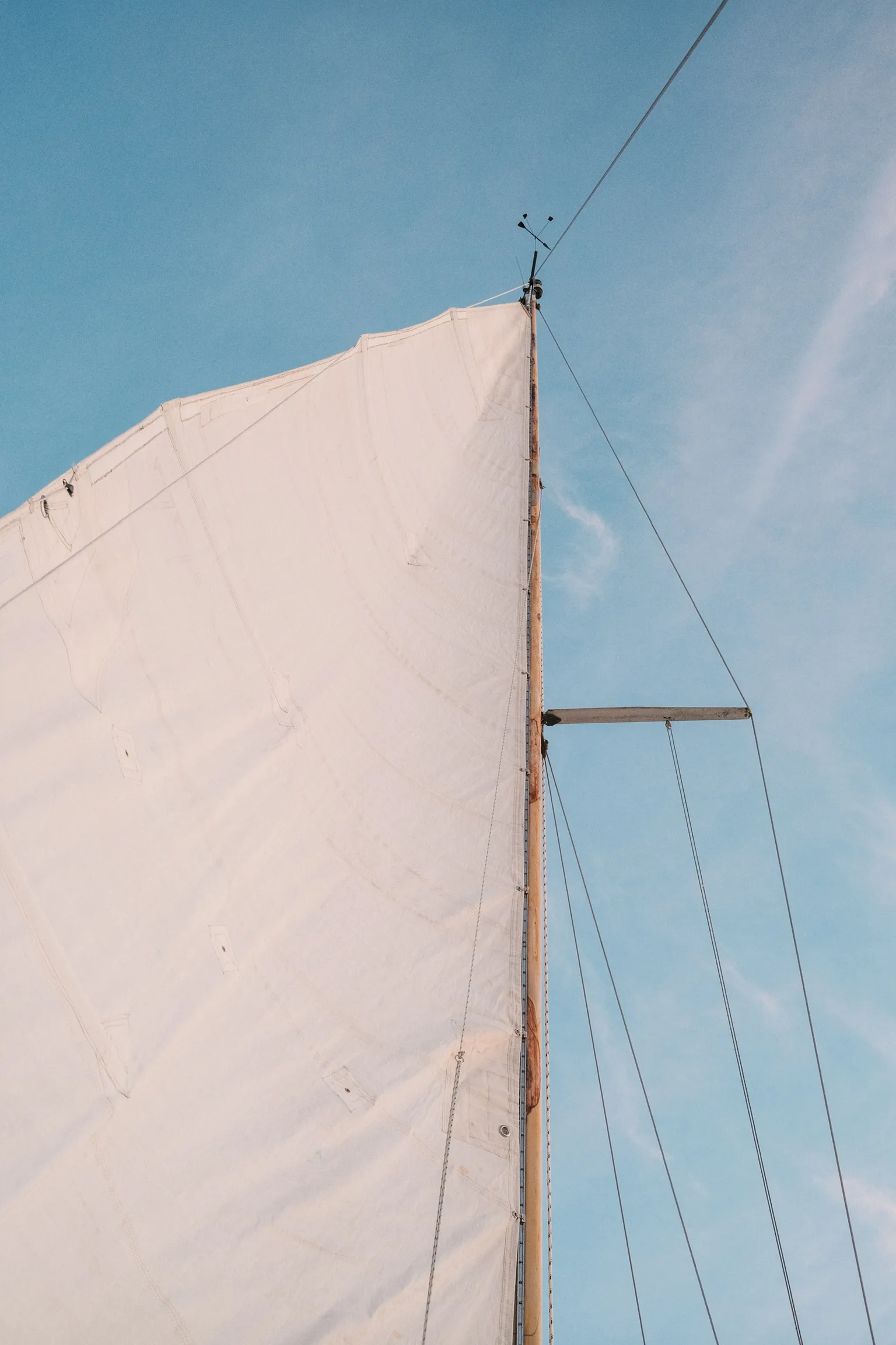 Close-up of white sails billowing against a bright blue sky